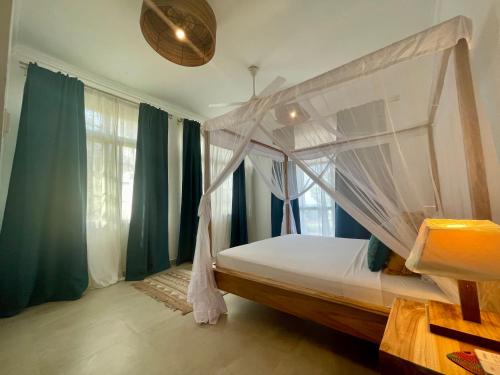 a bedroom with a canopy bed with green curtains at Ocean Boutique Hotel in Pingwe