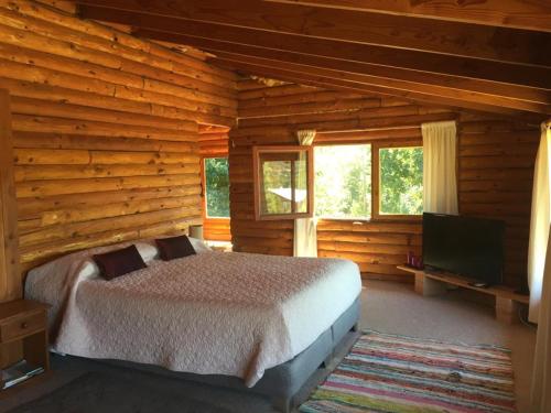 1 dormitorio con 1 cama en una cabaña de madera en Casa de Campo, en Villarrica