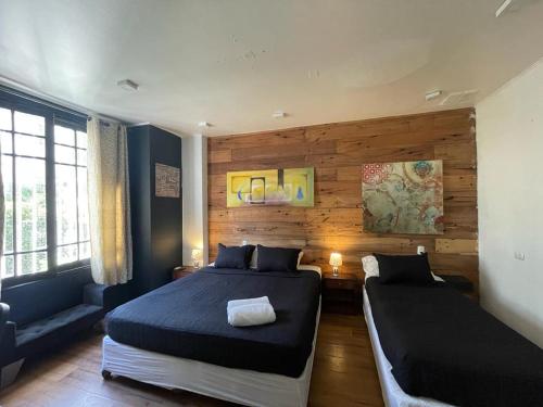 a bedroom with two beds in a room with wooden walls at Hotel Boutique Tremo Bustamante in Santiago