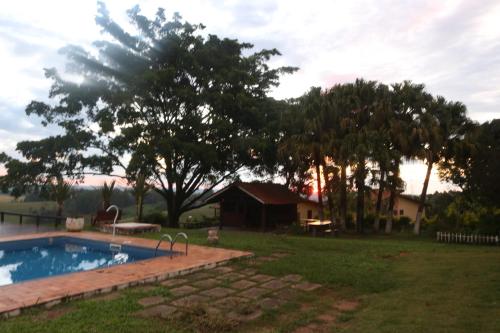 a swimming pool in a yard with trees and a house at Recanto das Seriemas in Patrimônio São Sebastião