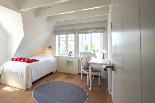 Schlafzimmer mit einem Bett, einem Schreibtisch und einem Fenster in der Unterkunft Funkelstern in Oldsum