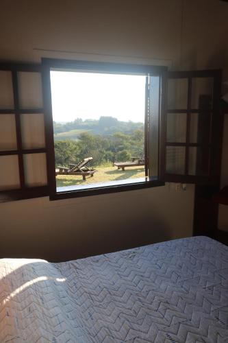 a bedroom with a large window with a view at Recanto das Seriemas in Patrimônio São Sebastião