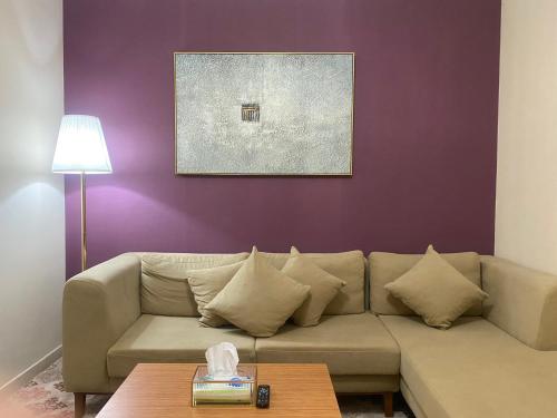 ein Wohnzimmer mit einem Sofa und einer lila Wand in der Unterkunft شقه ١١٢٢ في ابراج التلال بمكه المكرمه in Mekka