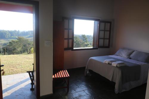 a bedroom with a bed and a window with a view at Recanto das Seriemas in Patrimônio São Sebastião