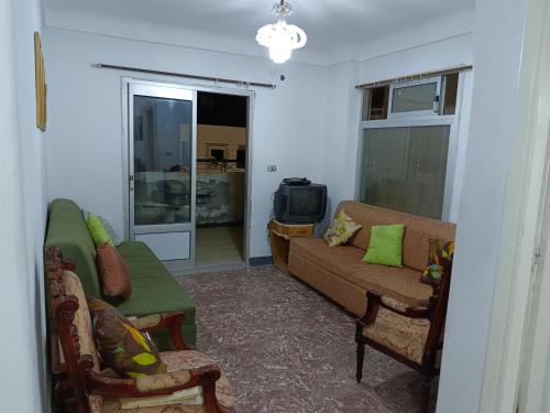 a living room with a couch and a tv at The sea apartment in ‘Izbat al Qaşr