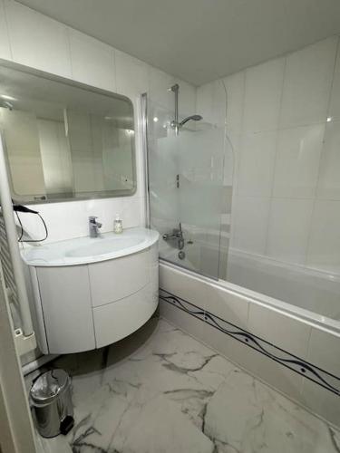 une salle de bain avec un lavabo, une baignoire et un miroir dans l'établissement Duplex près des Champs-Élysées, à Paris