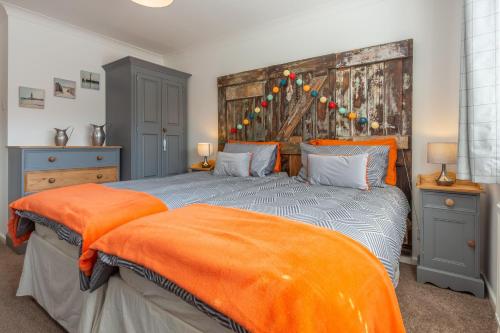 a bedroom with two beds with orange sheets at One Lazy Duck in Heacham