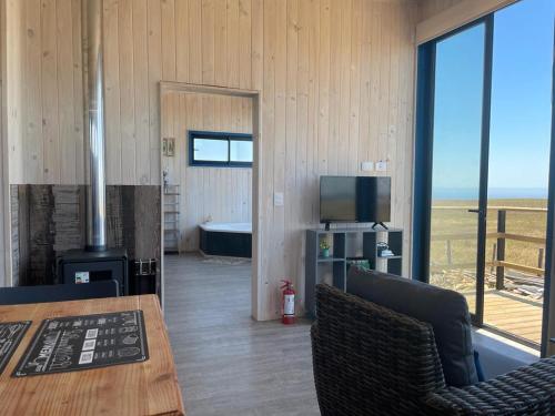 Habitación con chimenea, mesa y TV. en Cabaña con jacuzzi campo mar en Matanzas