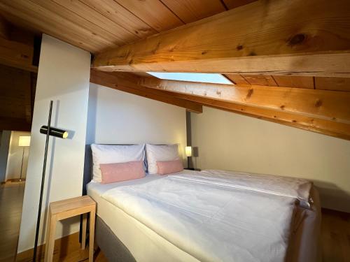 Ce lit se trouve dans une petite chambre dotée de plafonds en bois. dans l'établissement Apartment mit Zugspitzblick, à Grainau