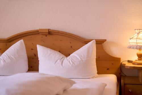 a bed with white pillows and a wooden headboard at Hotel der Löwen in Staufen in Staufen im Breisgau