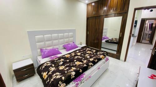a bedroom with a bed with purple pillows and a mirror at SBV Homes in Kharar