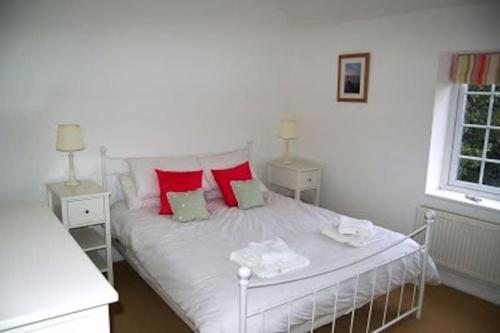 a white bed with red pillows in a bedroom at Gorgeous Cottage by the sea sleeps 10 5 bed 4 bath in Heacham