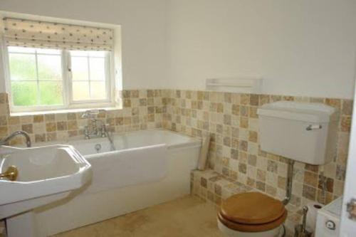 a bathroom with a tub and a toilet and a sink at Gorgeous Cottage by the sea sleeps 10 5 bed 4 bath in Heacham