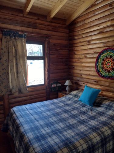 een slaapkamer met een bed in een blokhut bij Cabaña Sonnentahl in Potrerillos