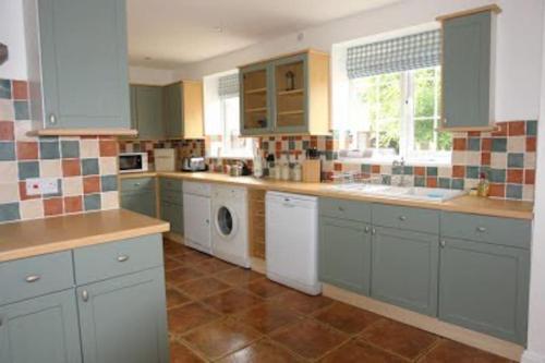 a kitchen with blue cabinets and a washer and dryer at Gorgeous Cottage by the sea sleeps 10 5 bed 4 bath in Heacham