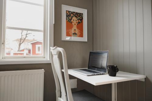 a laptop computer sitting on a white desk next to a window at Epokgården in Öregrund