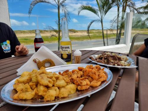 a table with two plates of food and two bottles of beer at Pousada Ykapê in Ilha Comprida