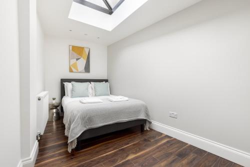 1 dormitorio con 1 cama en una habitación blanca en The Peckham Apartments, en Londres