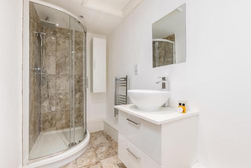 a white bathroom with a sink and a shower at The Peckham Apartments in London