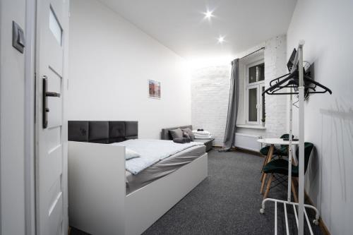a white bedroom with a bed and a window at Revolution Aparts - Rewolucji 27 in Łódź