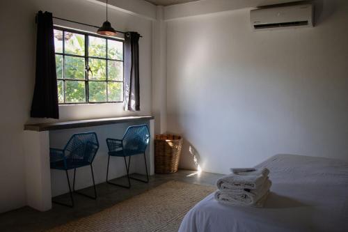 a bedroom with two blue chairs and a window at Soiree in Zipolite