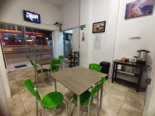 a restaurant with two tables and green chairs at alborada cuenca hospedaje in Cuenca