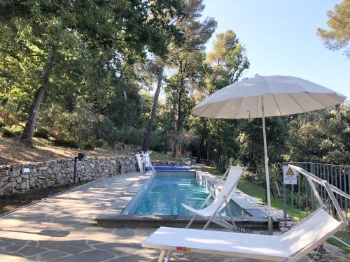 a swimming pool with two chairs and an umbrella at Casa nel bosco sul Golfo dei Poeti - Mago in Monte Marcello