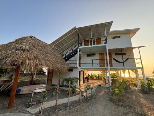 uma casa na praia com um telhado de palha em Stella Mar Oceanfront Hotel em Popoyo