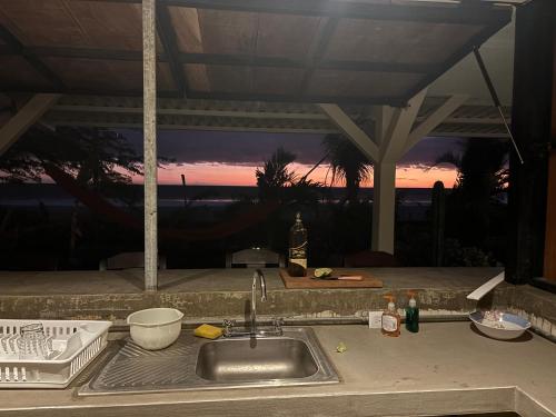 Stella Mar Oceanfront Hotel في بوبويو: حوض المطبخ مع غروب الشمس في الخلفية