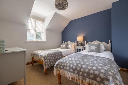 a bedroom with two beds and a blue wall at Owl Cottage W in Warham