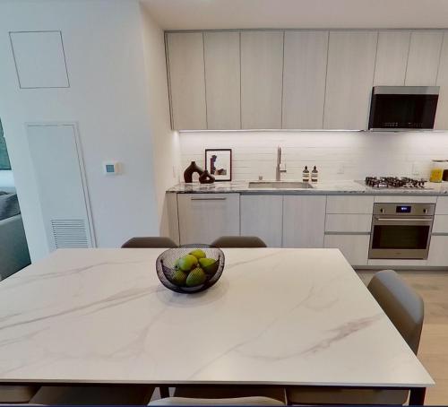 a kitchen with a table with a bowl of fruit on it at Level Long Beach - East Village in Long Beach