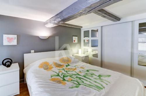 une chambre avec un lit blanc avec des fleurs dessus dans l'établissement Spacieux Duplex - Zone Piétonne, à Nice