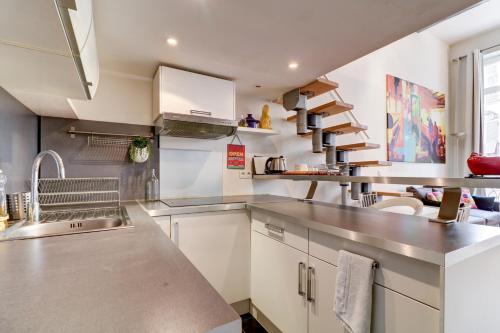 une cuisine avec des placards blancs et des comptoirs en acier inoxydable dans l'établissement Spacieux Duplex - Zone Piétonne, à Nice