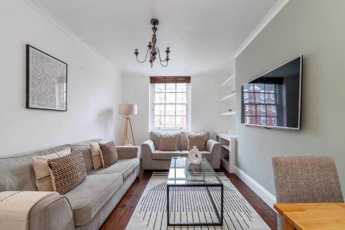 a living room with a couch and a tv at The St John's Wood Apartment in London