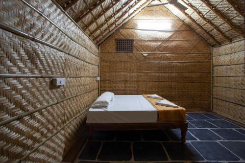 Habitación pequeña con cama en una pared de madera. en Hampi Social Resort en Hampi