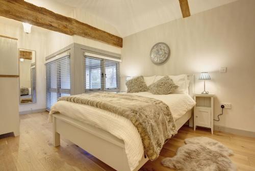 um quarto com uma cama e um relógio na parede em Owlets at Mulberry Barn em Heacham