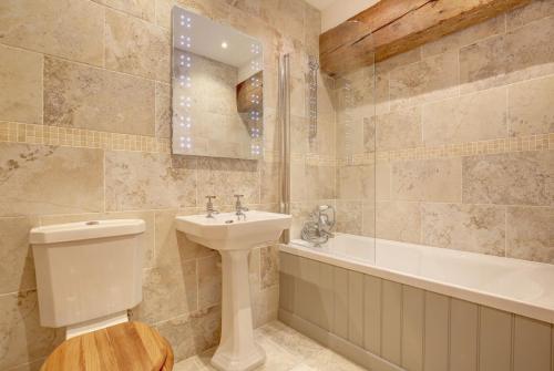 uma casa de banho com um lavatório, um WC e uma banheira em Owlets at Mulberry Barn em Heacham