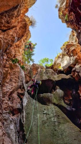 a person is rappelling down a rocky cliff at Orionas in Tsoútsouros