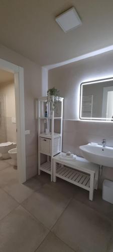 a white bathroom with a sink and a mirror at Guest House Palazzo Buoninsegni in Colle Val D'Elsa
