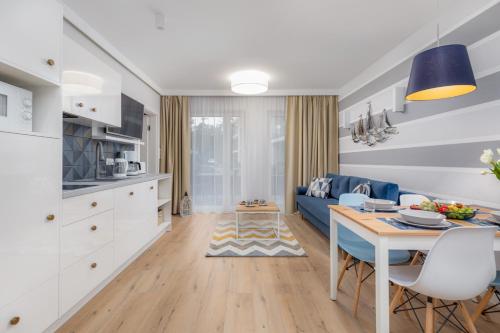 a kitchen and living room with a blue couch and a table at Pobierowo Beach Baltic Apartment with Pool by Noclegi Renters in Pobierowo