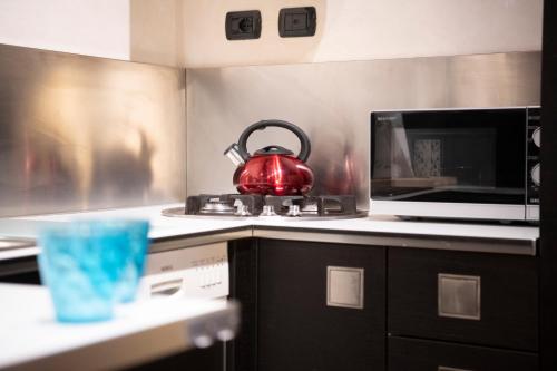 a red tea kettle sitting on a stove in a kitchen at Ai piedi del castello / 4PL / Apt. FULL in Verona