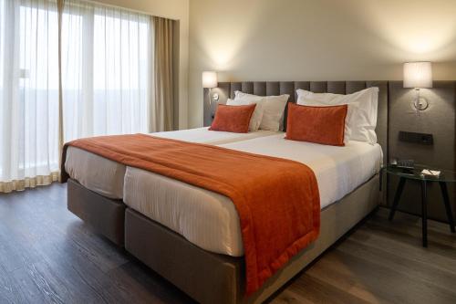a hotel room with a large bed with orange pillows at Hotel Versatile in Guarda
