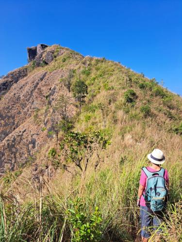 a man with a backpack walking up a hill at Munnar Village Homes in Munnar