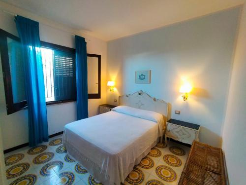 a bedroom with a bed and a window with blue curtains at Casa&Mare Mazara del Vallo in Granitola