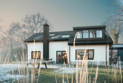 a house with a picnic table in front of it at Vakantiepark De Boshoek - Luxe Groepsverblijven op de Veluwe in Voorthuizen