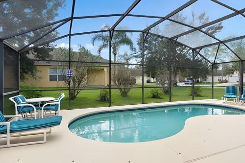 a swimming pool with chairs and a table and a table and chairs at Quiet house with pool on a Top golf course in Haines City