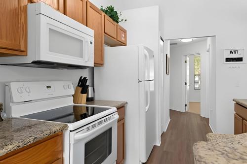 a kitchen with white appliances and wooden cabinets at Quiet house with pool on a Top golf course in Haines City