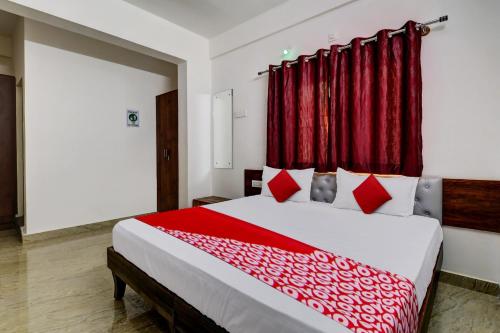 班加羅爾的住宿－OYO 82074 Hotel Aishwarya Comfort，一间卧室配有一张带红色窗帘的大床