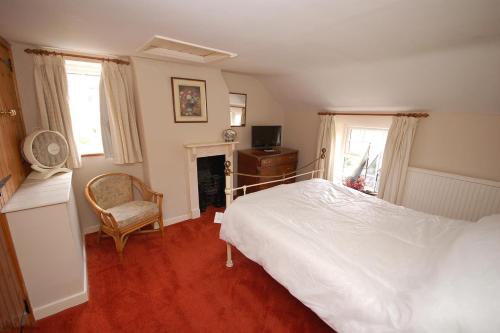 1 dormitorio con 1 cama blanca y 1 silla en Romany Rye, en Sheringham