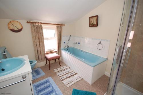 y baño con bañera azul y lavamanos. en Romany Rye, en Sheringham